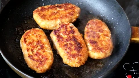 Four cutlets are fried in a frying pan in a large amount of oil Stock Footage 297934982
