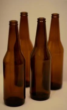 Four dark empty beer bottles on the table. Stock Photos