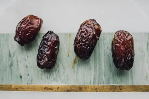 Four dates, fruit on green, marble, brass cheese board 스톡 사진