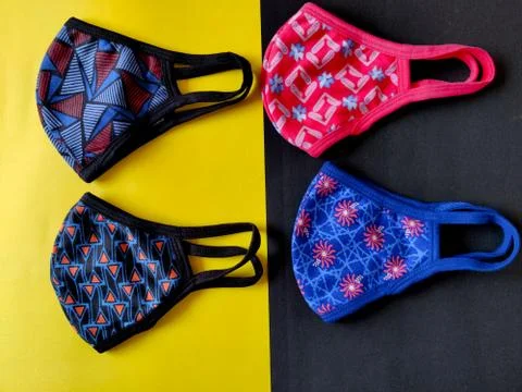 Four different colored printed face masks isolated on yellow and black backgr Stock Photos