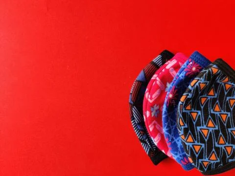 Four different colored printed face masks isolated on red background. Copy sp Stock Photos