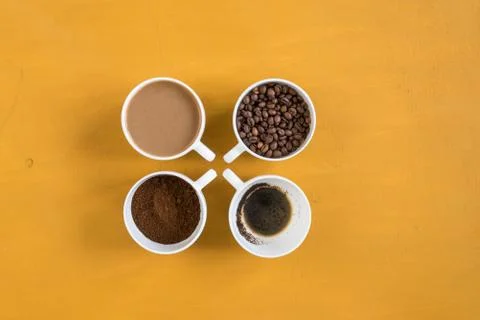 Four different cups on a yellow background Stock-Fotos