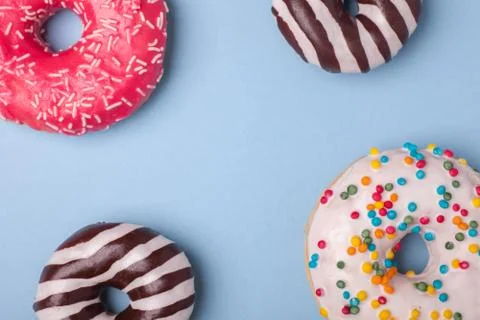 Four different donuts isolated on blue background Stock Photos