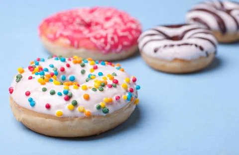 Four different donuts isolated on blue background Stock Photos