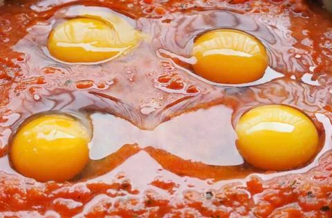 Four eggs in tomato sauce Stock Photos
