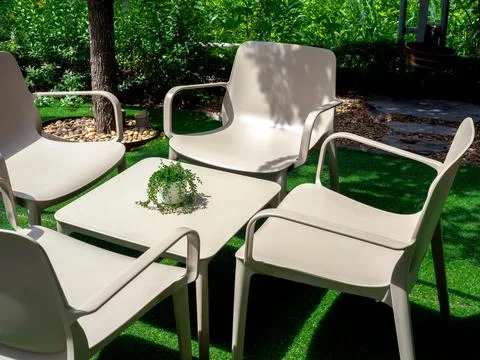 Four empty beige plastic chairs with square shape table with small plant pot  Stock Photos