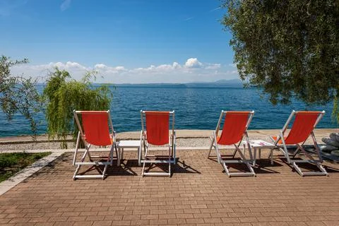 Four Empty Deck Chairs on a beautiful beach on Lake Garda - Veneto Italy Stock Photos