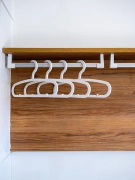 Four empty white plastic cloth hangers without shirts or dress hanging on a.. Stock Photos