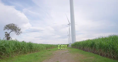 Four engineers in high visibility safety uniform walking to wind turbine, Stock Footage 321048250