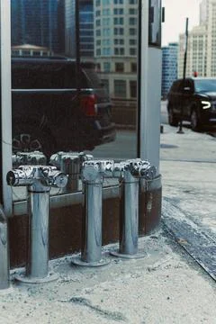 Four fire hydrants sit next to a building on a city street with tall building Stock Photos
