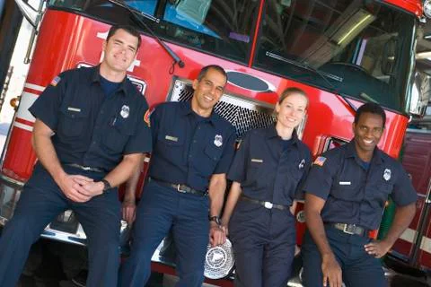 Four firefighters leaning on fire engine Stock Photos