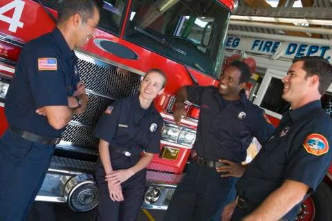 Four firefighters talking by fire engine Stock-Fotos