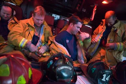 Four firemen in fire engine putting on gear (blur) Stock Photos
