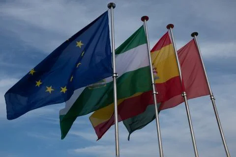 Four flags fluttering in the wind are the European Union, Spain, Granada and  Stock Photos