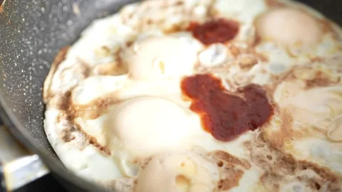 Four fried eggs are being cooked in a black speckled frying pan Stock Footage 346989272