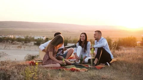 Four friend having fun at summer picnic, drinking a bottle of beer. Stock Footage 138741188