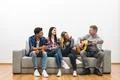The four friends drink a beer and play the guitar on the white wall backgroun Photo