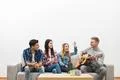 The four friends with a guitar sit on the sofa on the white wall background Photo