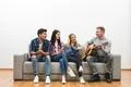 The four friends with a guitar sit on the sofa on the white wall background Photo