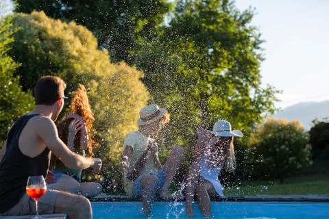 Four friends having fun at the pool edge in the garden Stock Photos