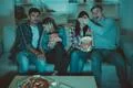 The four friends with a popcorn watch a horror film on the sofa Photo
