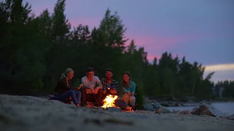 Four friends roasting marshmallows at sunset Stock Footage 115276377