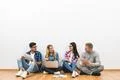 The four friends sit on the floor on the white wall background Photo