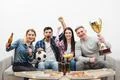 The four friends on the sofa watch a football on the white background Photo