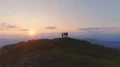 The four friends standing on the mountain top against a beautiful sunset 4k or 4k+ Resolution