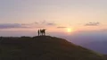 The four friends standing on the mountain top against the beautiful sunset 4k or 4k+ Resolution