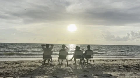 Four Friends Watch Sunset From Beach Chairs on Florida Coast Stock Footage 345965398