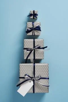 Four gift boxes of different sizes are lined up on a pastel blue background.. Stock Photos