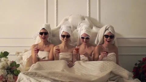 Four girlfriends are in the same bed with towels on their heads Stock Footage 101118891