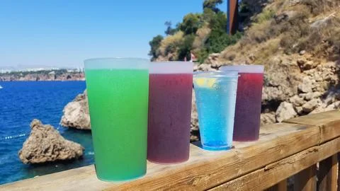 Four glasses with various multi-colored cocktails stand on a wooden railing Stock Photos