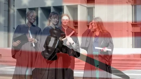Four graduates walking campus steps, pulling phone and posing for selfie, flag Stock Footage 333873474