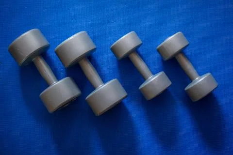 Four grey dumbbells of two different sizes Stock Photos