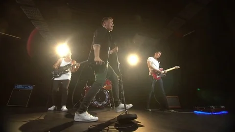 Four guys are in a rock band and perform in the studio Stock Footage