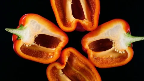 Four half sliced red bell peppers rotate on black background. 4K Vídeos de archivo 74060130