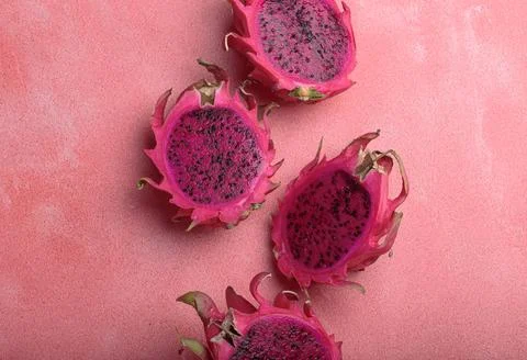 Four halves of dragon fruit lying on pink background top view Stock Photos