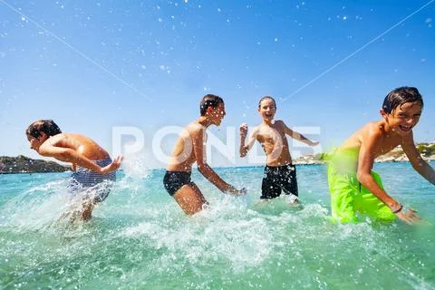 Four happy boys playing at tropical shallow water Stock Photos