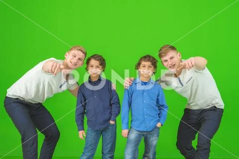 The four happy brothers stand on the green background and gesture Stock Photos