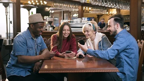 Four happy caucasian friends using smart phone together in the bar, pub. Stock Footage 109163364