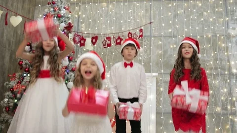 Four happy children jumping next to the decorated Christmas tree and throwing Stock Footage 83300972