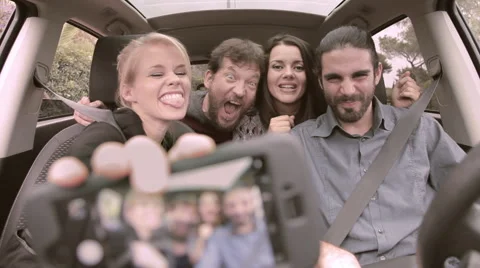 Four happy cool friends taking selfie with phone in car Stock Footage 56057110