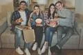 The four happy friends with a popcorn and a pizza watch a film on the sofa Photo