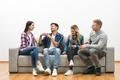 The four happy friends on the sofa play the game on the white wall background Photo