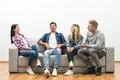 The four happy friends on the sofa play the game on the white wall background Photo