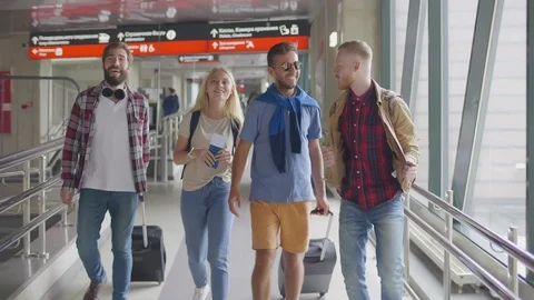 Four happy friends talking while walking in modern international airport Stock Footage 121323485