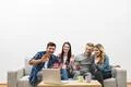 The four happy people gesture near laptop on the white wall background Photo