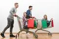 The four happy people ride on the cart on a white wall background Photo